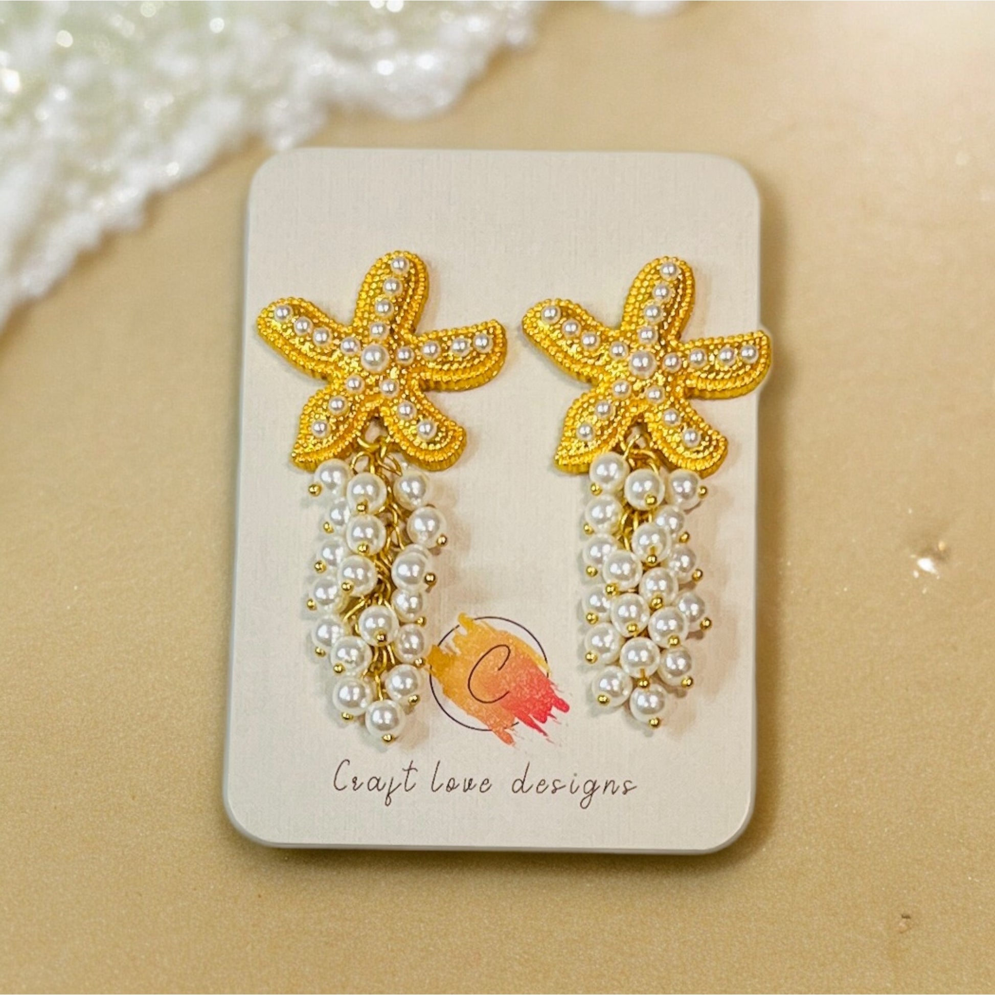Elegant boho sea star earrings featuring gold-tone beaded starfish and cascading pearl accents, creating a chic ocean-inspired statement. 