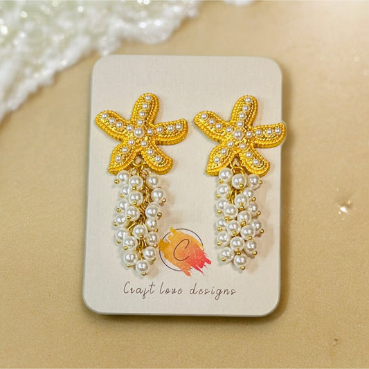 Elegant boho sea star earrings featuring gold-tone beaded starfish and cascading pearl accents, creating a chic ocean-inspired statement. 